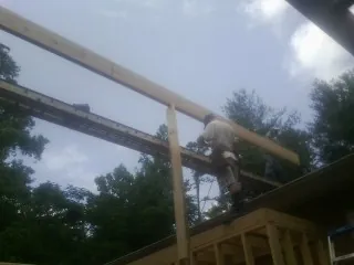 Carpenter setting a ridge beam over a new addition frame — Ice Dam Removal by Roofing Brothers in Millsboro
