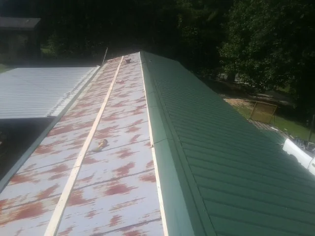 Old rusted panels beside newly installed green metal roofing — Wind Damage Roof Repair by Roofing Brothers in Millsboro