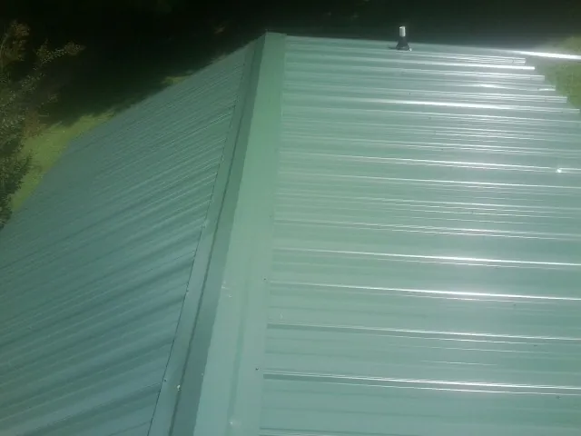 New green metal panels meeting at the ridge of a roof — Flat Roof Repair work by our crew in Millsboro