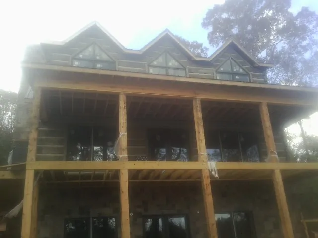 Dormers and porch framing on a large log home under construction — Roof Coating work by our crew in Millsboro