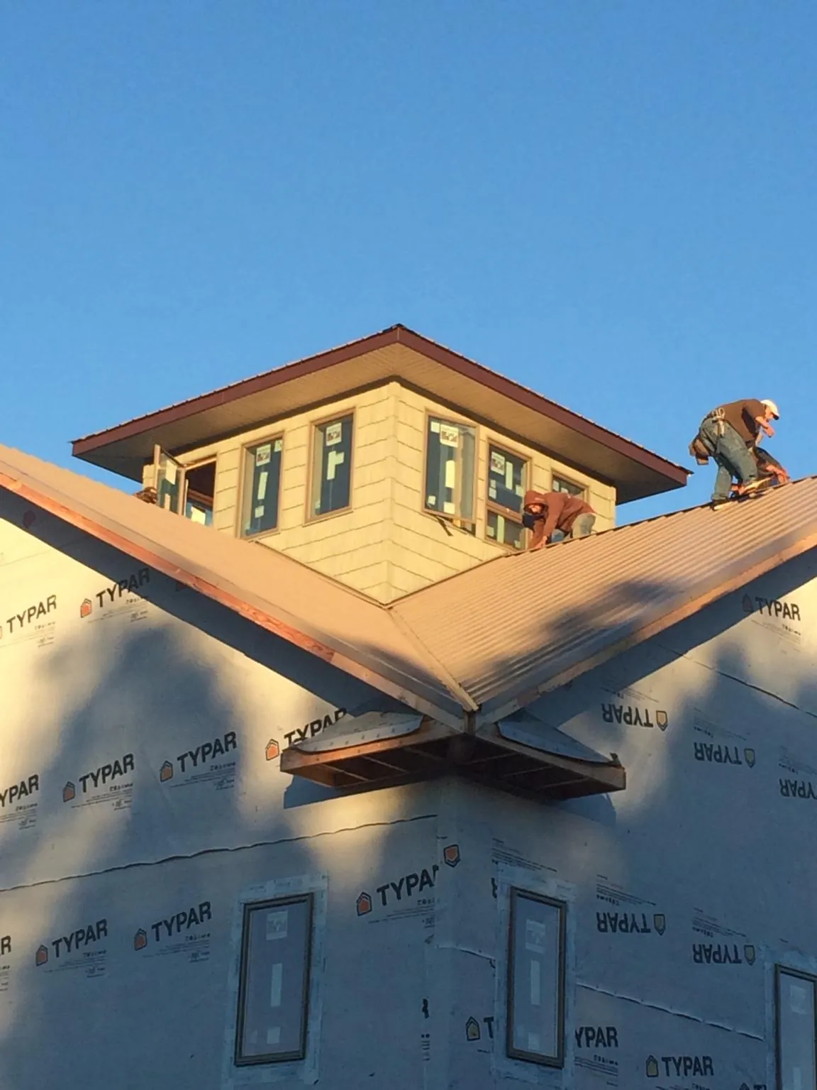 Roofers working around a rooftop cupola on a new metal roof at sunset — Roof Waterproofing in Millsboro by Roofing Brothers